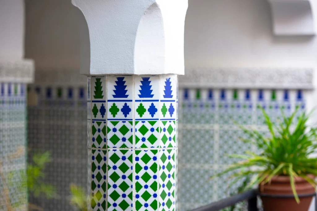 Traditional Moroccan column with green and blue zellige tiles in a riad in Rabat