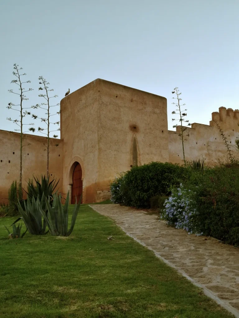 Ancient Merinid walls and gardens at Chellah in Rabat, Morocco, with a stork perched on the tower at dusk
