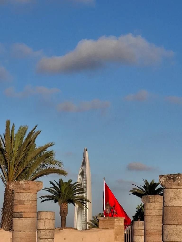 Mohammed VI Tower in Rabat seen with Moroccan flag and palm trees