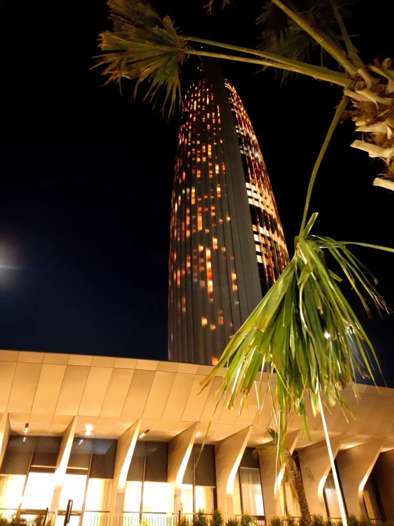 Mohammed VI Tower in Rabat illuminated at night with palm trees