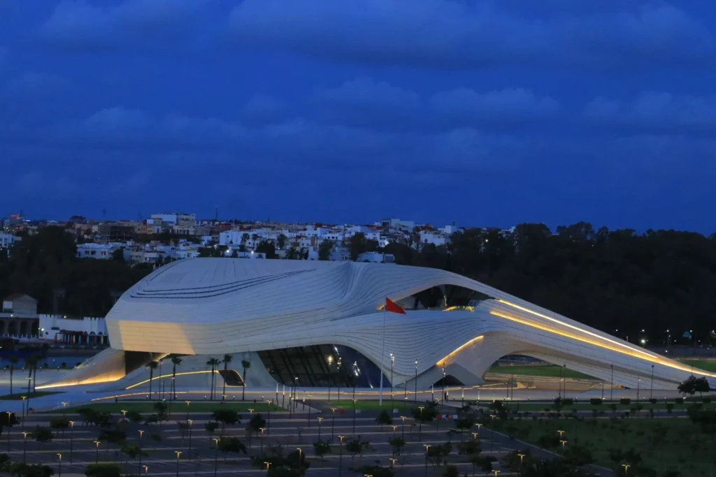 The illuminated Royal Theatre of Rabat designed by Zaha Hadid Architects captured during the blue hour with its futuristic curved facade glowing.