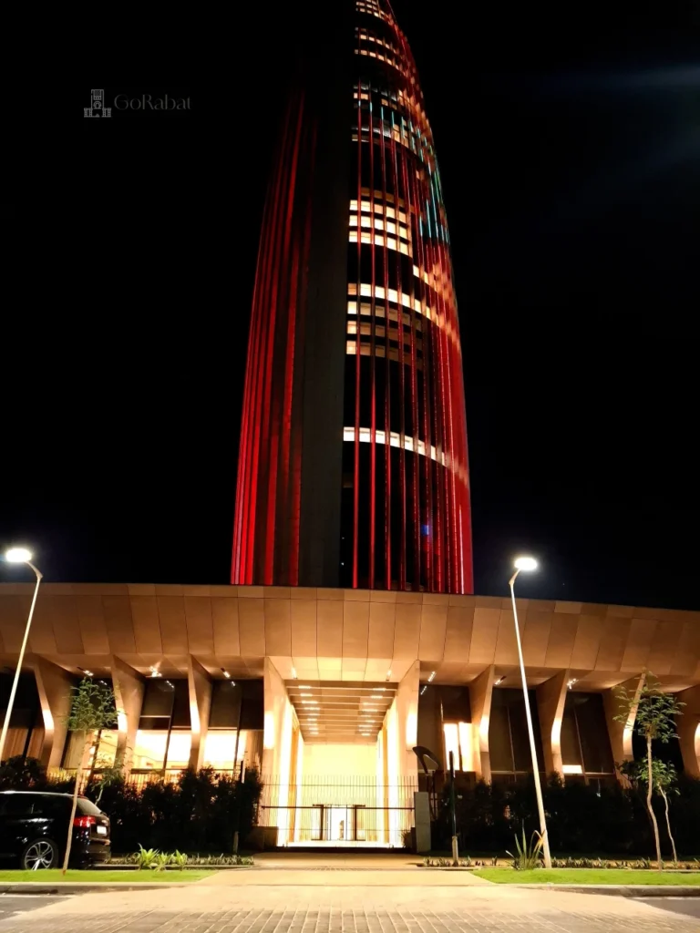 The spectacular Mohammed VI Tower at night illuminated in vibrant red and green to display the Moroccan national flag, showcasing modern architecture in Rabat-Salé.