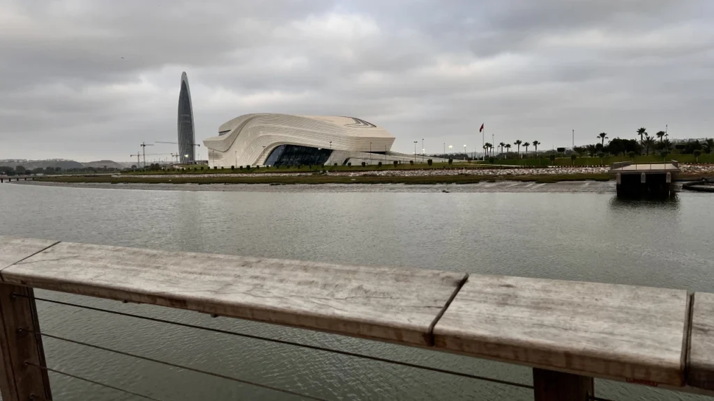 View from the green lawns and wooden boardwalk of the new park of Salé looking across the Bouregreg river toward the futuristic Royal Theatre of Rabat and the tall Mohammed VI Tower.